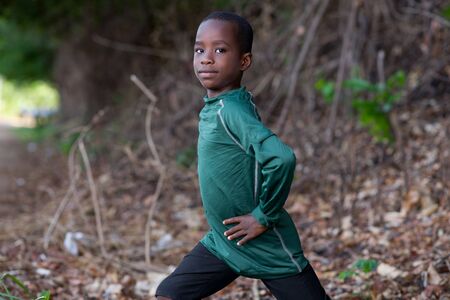 Little athletic boy warming up and stretching alone at the park. Lifestyle and sport conceptの写真素材