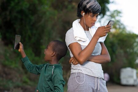 mother and son uses mobile phone outdoors after a fitness session togetherの写真素材