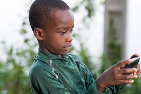 Young boy child with mobile phone outdoors. Child looking at the screen, playing, using apps.の写真素材