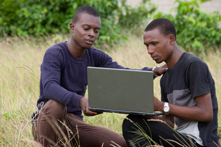 two young students discuss and plan their work on a laptop in nature..
