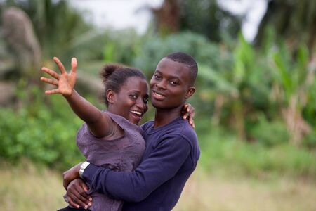 young african couple standing in an intertwined park smiling at the camera.の写真素材