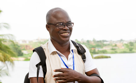 mature man standing in glasses, backpack smiles at the camera.