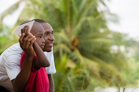 little boy in red t-shirt standing near his father in front of them looking smiling.の写真素材
