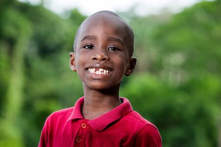 Close Up portrait of little cute funny boy looking at camera while smiling while playing outdoors on hot summer day. Horizontal color photography.の写真素材