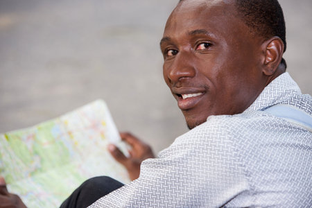 young man in shirt sitting with map looking at camera smiling.