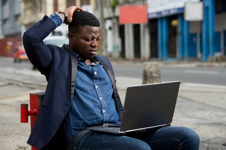 young man sitting in jacket looking at laptop.の写真素材