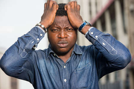 young african man standing in jeans staring at the camera with his face frowning on his head.の写真素材