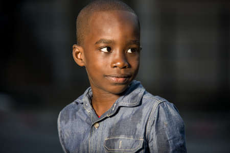 Close-up of a young boy with a smile on his face and looking at his side at nightの写真素材