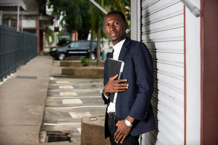 young african man standing in a suit looking at camera smiling.