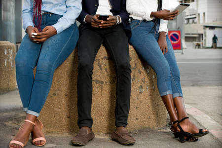group of young people sitting in jeans pants with mobile phones.の写真素材