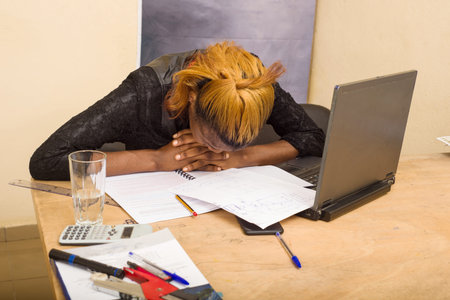 young woman sitting at the desk with her head resting on the table.