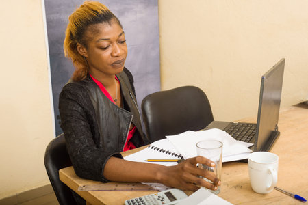 portrait of a beautiful young woman drinking water at the workplace. hard work concept.
