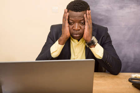 young businessman sitting at desk looking at computer looking sad.の写真素材