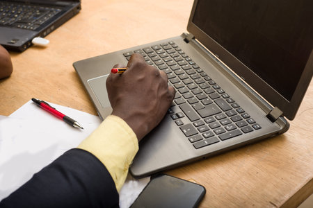 close-up of a businessman's hand resting on a desk on computer keyboard
