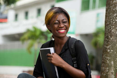 young student sitting in a shirt laughing with notebook in hand closed eyes.の写真素材