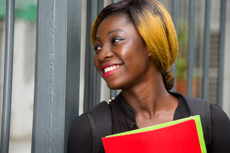 student standing near grid with documents watching something smiling.