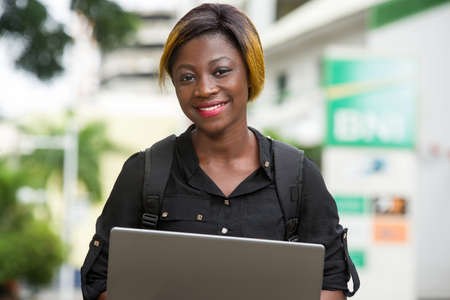 student sitting with laptop watching camera smiling.の写真素材