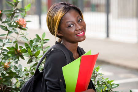 young student sitting with backpack watching the camera smiling.の写真素材