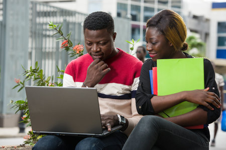 Education concept - Students, girl and boy do their homework using a laptop or documents as research...