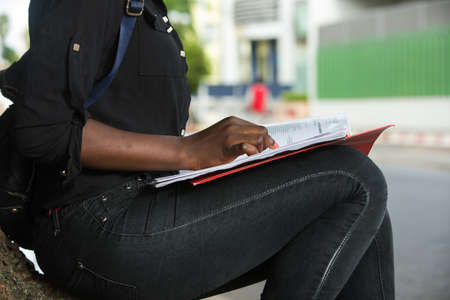 Female student writing and working outdoors at the park a text in the notebook.の写真素材