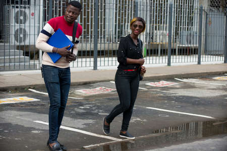 woman and an education man or students discuss after school instructions while walking together on the streetの写真素材