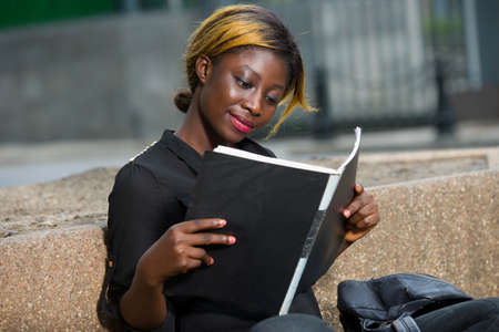 Young girl doing her chores and homework sitting on campus outside. College studentの写真素材