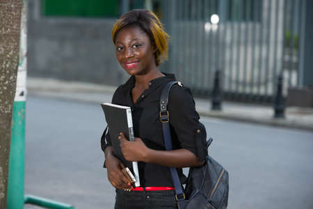 young student standing with backpack watching the camera smiling.の写真素材