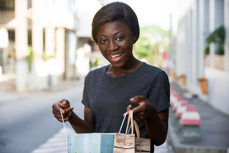 young happy woman standing in an urban environment and carrying shopping bags.の写真素材
