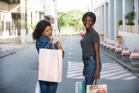 two cheerful girls walking down the street after shopping at the mallの写真素材