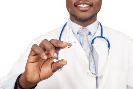 male doctor standing in glasses with stethoscope on the neck and smiling syringe, ready to give medical treatment to the patient.の写真素材