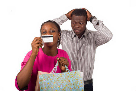 Smiling woman and a man standing and holding shopping bags and a credit card for online shopping or...
