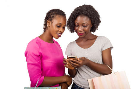 Portrait of happy women holding colorful shopping bags and communicating on smart phone in hands isolated on white backgroundの写真素材