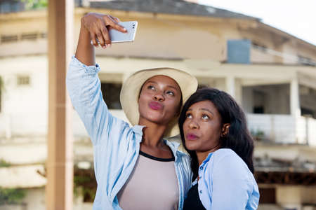 young girlfriends standing up to photograph themselves smiling.の写真素材