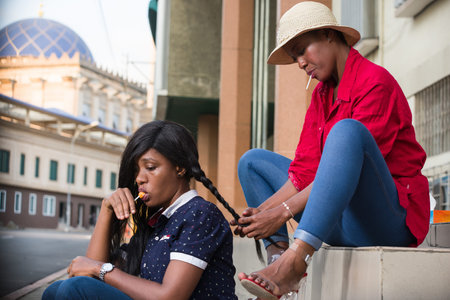 young girl sitting on a staircase playing with her friend's wick with sweet lollipop in mouth.