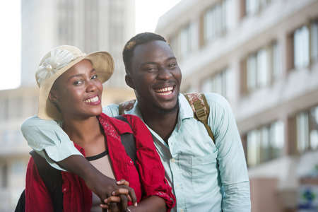young couple of tourists going for a walk in a street of the city laughing.の写真素材