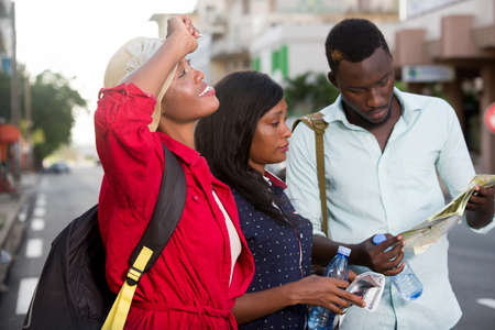 group of young tourists standing in the street with map.の写真素材