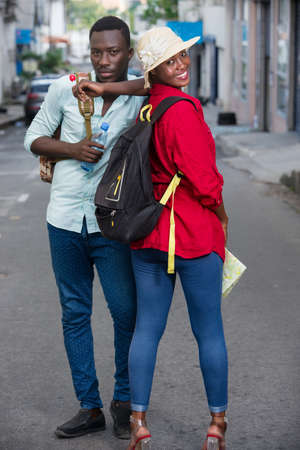 young couple standing in the street in jeans watching the camera smiling.の写真素材