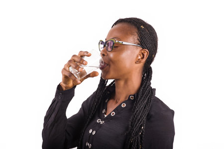 young woman standing on white background in glasses drink some water.