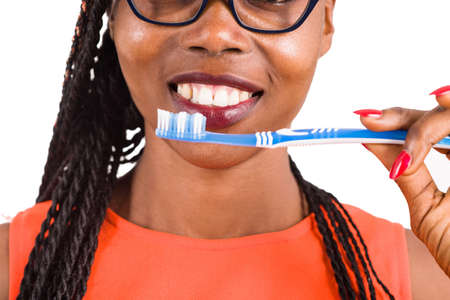 young girl standing in eyeglasses on white background smiling to hold a toothbrush to the mouth.の写真素材