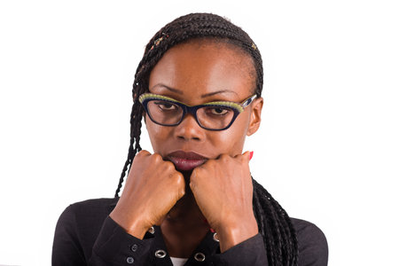 young african woman standing on white background looking at the camera with her hands under her...