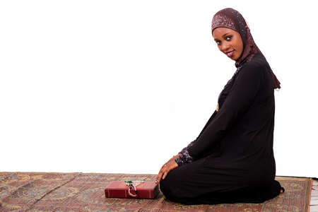 young muslim woman sitting on a mat smiling at the camera.の写真素材