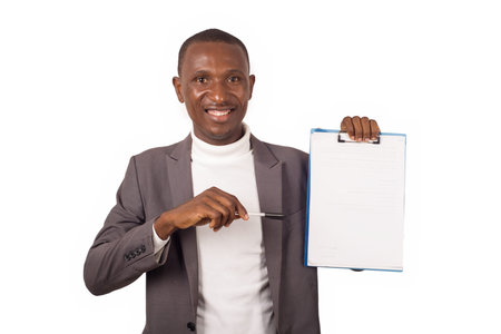 Portrait of young smiling man in suit standing on white background showing something on a notepad in...