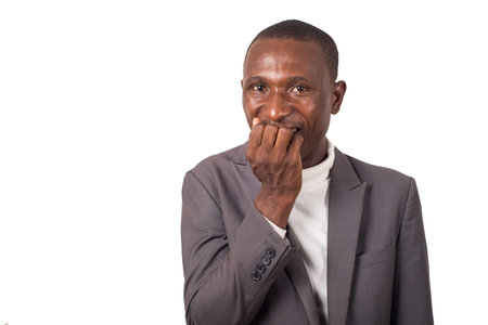 portrait of young man in suit biting fingers standing and isolated on white background.