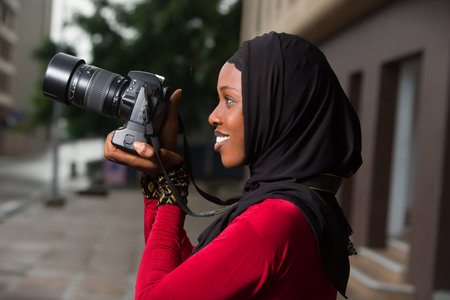 young muslim woman standing outdoors looking at camera smiling.