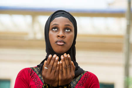 young muslim woman standing outdoors praying.の写真素材