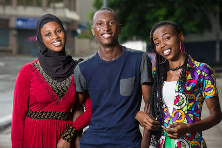group of young people standing outdoors looking at camera laughing.の写真素材