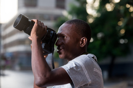 young man standing outdoors looking at camera smiling.