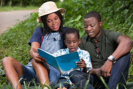 a family sitting in the grass watching pictures with their children smiling.の写真素材