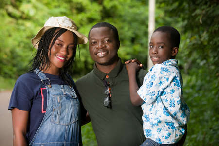 a family standing in a park watching the camera smiling.の写真素材