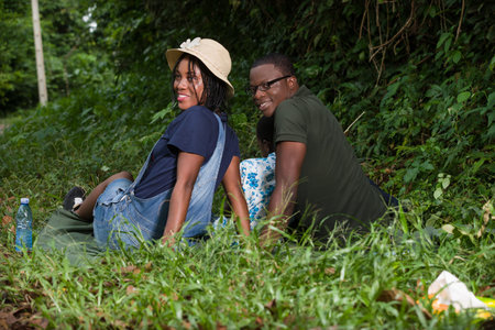 young family sitting in a park looking in profile while smiling.